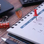 Kalender dan penanda di meja untuk perencanaan waktu dan tempat acara